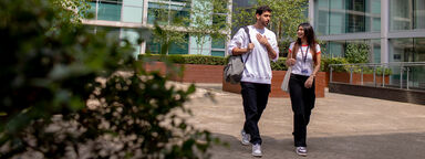 Two students walk away from the building at 3 Solly Street. It is bright and sunny, and they are chatting to one another.