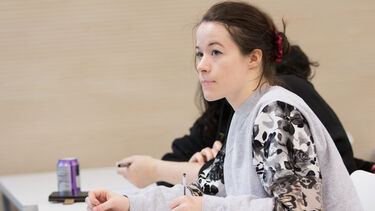 DLL mature student taking notes in a seminar 