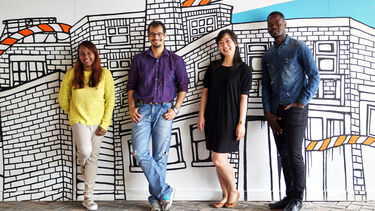A group of students stood infront of a mural