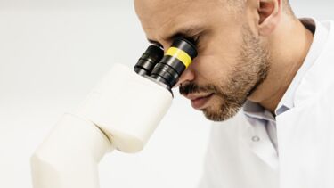 A man observes through a miscroscope.