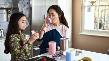 Teenage girl looking at fruit drink with satisfied expression