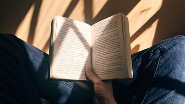 Person sat cross-legged, reading a book