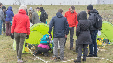 Workshop participants working around tents in a field