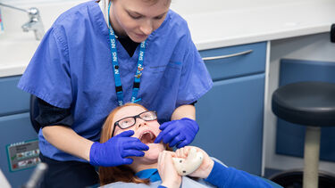 Child squeezes stress toy as her teeth are looked at by female dentist