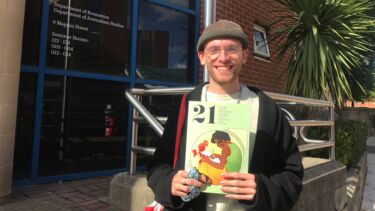 Student showing magazine with big smile