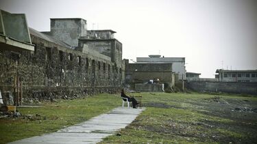 A person sat on a bench outside ruins