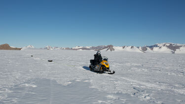 A snowmobile travelling across Antarctica with a radar survey attached to locate and examine subglacial lakes
