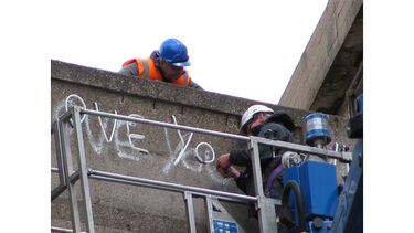 Workman installs the neon sign over the graffiti