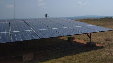 a large set of solar panel sits on dry arid grassland in tanzania. The are quite high above the ground. 