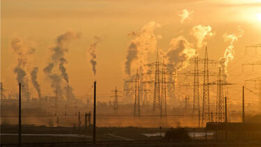 Electricity pylons and chimneys with plumes of smoke