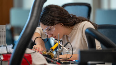 Photograph of Ece soldering during the Hackathon
