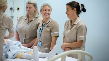 A group of nursing apprentices stood next to a hospital bed