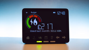 a smart meter on a wooden table shows an energy cost reading