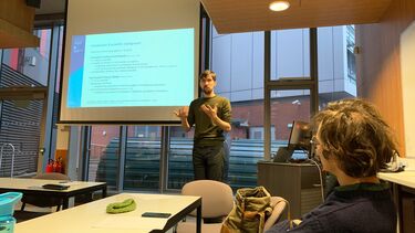 Andres Hiemstra in front of a screen with example sentences giving a presentation