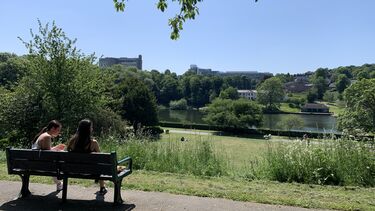 view on a Sheffield park in late spring. Two people sitting on a bench in the foreground