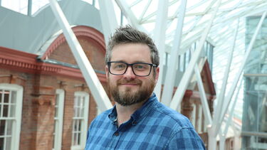 A white man in a blue checked shirt wearing glasses
