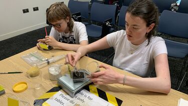 Two students at a table carefully weighing black powder