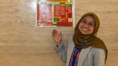 Dwi standing infront of their Poster 