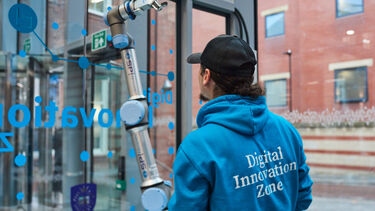 Student with blue hoody using a robort arm 