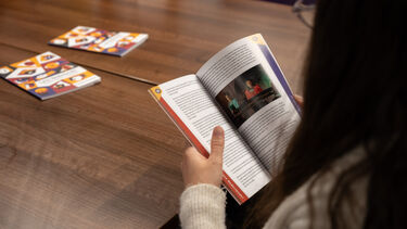looking over the shoulder of a person reading the publication Leve Nederlands! 75 years of Dutch in 15 portraits