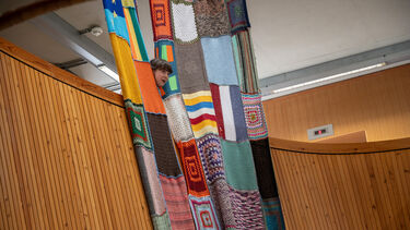 colourful curtains hanging down in Jessop West's architectural circles with a student performing part of the play 'Egel"