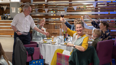 people sitting around a table raising their glasses dor a toast