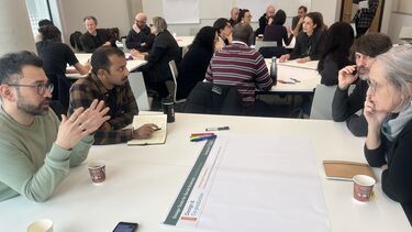 A group discussion around a table with flipchart paper and pens on it