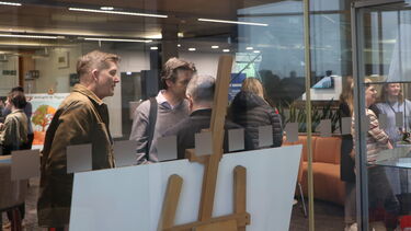 View from the Digital Commons to the exhibition space in the IC, with people looking at the artefacts