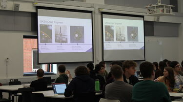 Students looking at a plasma screen about the UK Space Agency Chief Engineer