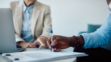 A person signing a contract, with a professional watching them.