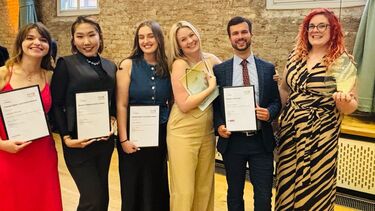 Six people stood full length holding awards.