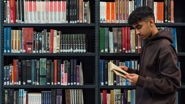 A student reading a book in Western Bank Library