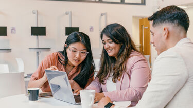 A group of students looking at a laptop