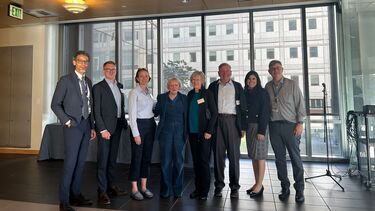 Colleagues from both the universities of Sheffield and Washington stand in a boardroom against a window and smile towards the camera.