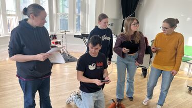 5 students rehearsing for the Dutch play. One on their knees.