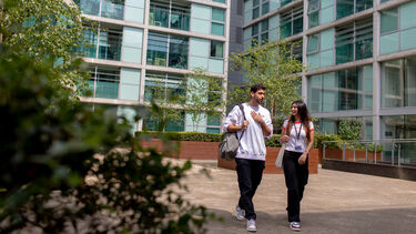 Two students walk away from the building at 3 Solly Street. It is bright and sunny, and they are chatting to one another.