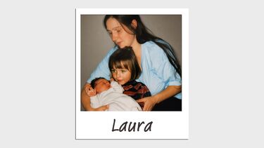 A mother sits with two children, a toddler and a baby