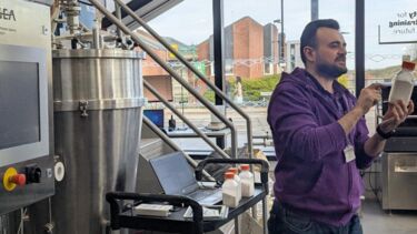 A researcher wearing a purple jumper is demonstrating the GEA bioreactor system at The Diamond