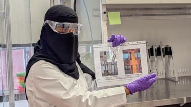 A PhD student in full PPE is delivering an outreach session about algae
