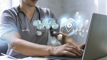 A doctor using a laptop computer with health related graphics in the air