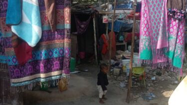 A child in his open-roof home with make-shift bamboos in places where walls were to be