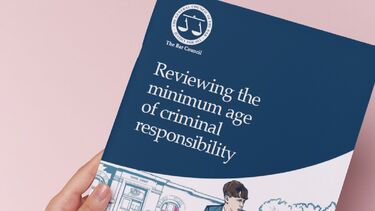 Photo of a booklet with the title 'Reviewing the age of criminal responsibility' and a cartoon of a young boy on a bike in school uniform'
