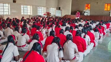 School assembly hall with students in red and white uniforms