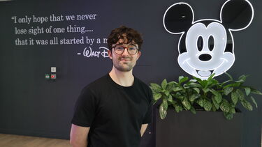 Placement student standing next to an LED Micky Mouse emblem