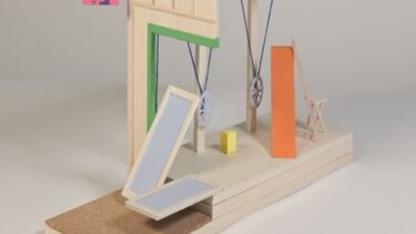 A wooden model of a pedal-powered machine with a flat table surface