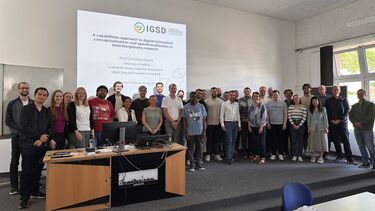 A group of people standing in front of a presentation screen at a lecture