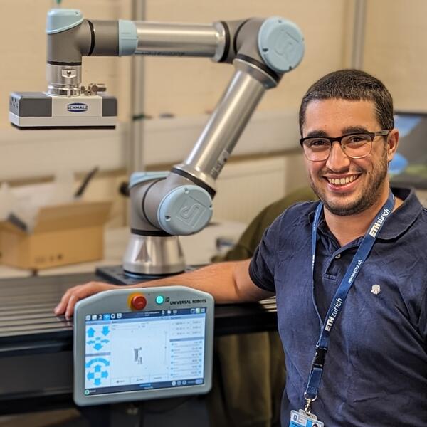 Profile picture of Smiling researcher sitting next to engineering equipment