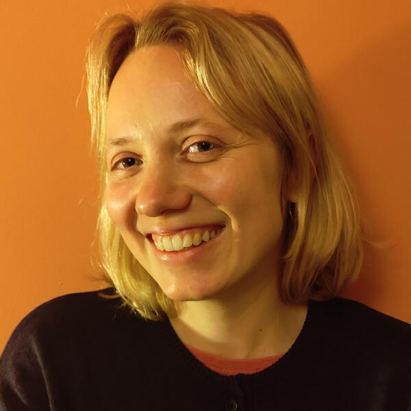 Profile picture of Mari- Liis standing in front of an orange wall smiling