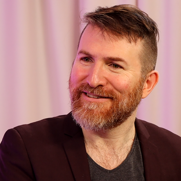 Profile picture of Alon is smiling and looking slightly off to the left at something off camera, wearing a dark blazer
