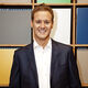 Journalism alumni Dan Walker. He is smiling and standing in front of some colourful blocks. 